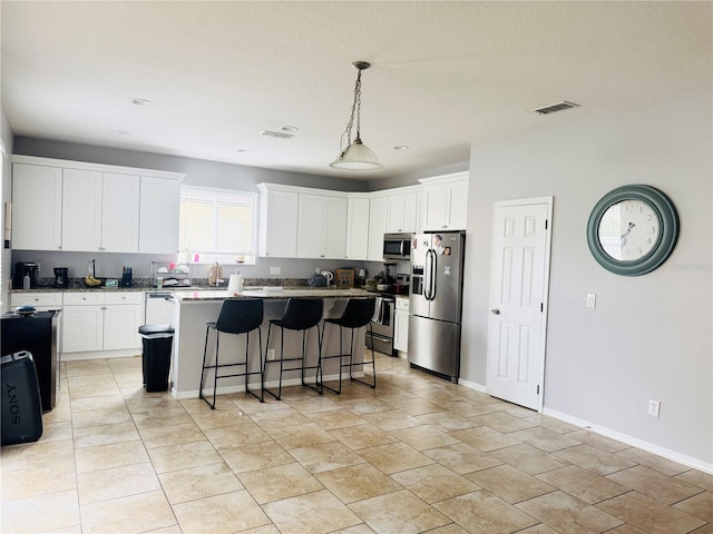 kitchen featuring stainless steel appliances, a center island, white cabinets, a kitchen bar, and decorative light fixtures