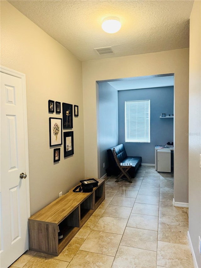 hall with light tile patterned flooring and a textured ceiling