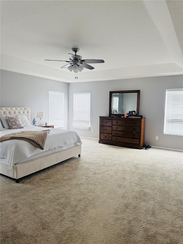 bedroom featuring carpet floors, a raised ceiling, and ceiling fan