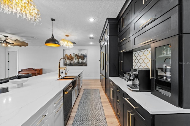 kitchen with sink, white cabinetry, decorative light fixtures, a textured ceiling, and light stone countertops