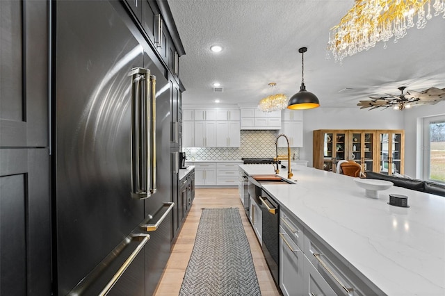 kitchen with built in fridge, decorative light fixtures, white cabinetry, decorative backsplash, and a textured ceiling