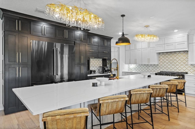 kitchen featuring pendant lighting, a large island, a breakfast bar area, and stainless steel refrigerator