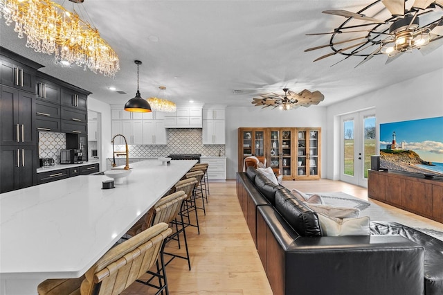 living room featuring french doors, sink, ceiling fan, a textured ceiling, and light hardwood / wood-style flooring