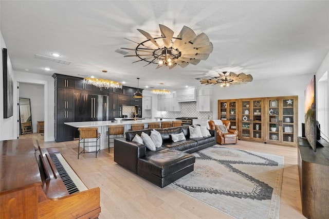 living room with sink, light hardwood / wood-style flooring, and ceiling fan