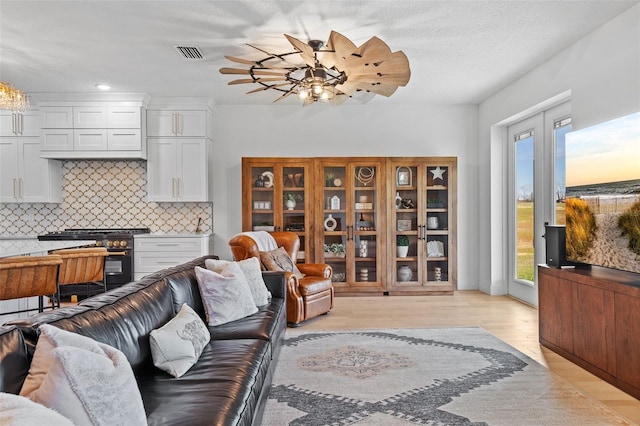 living room with a wealth of natural light, a textured ceiling, and light hardwood / wood-style flooring