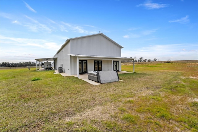 back of property featuring cooling unit, a lawn, and a rural view