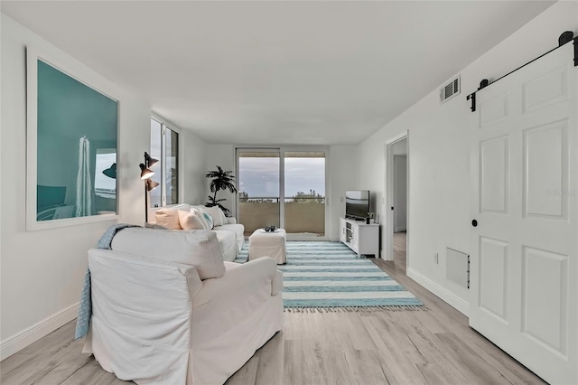 living room featuring a barn door and light hardwood / wood-style flooring