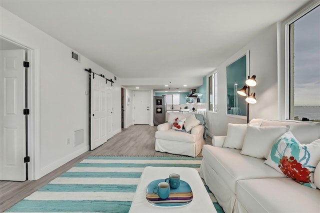 living room with a barn door and light hardwood / wood-style flooring