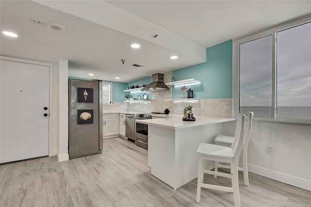 kitchen featuring a kitchen bar, extractor fan, stainless steel range with electric stovetop, light hardwood / wood-style floors, and white cabinets