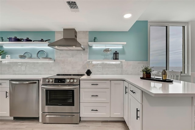 kitchen with appliances with stainless steel finishes, exhaust hood, white cabinets, and light wood-type flooring