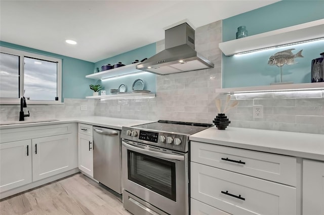 kitchen with sink, white cabinetry, stainless steel appliances, island range hood, and light hardwood / wood-style floors