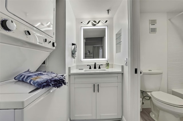 bathroom featuring vanity, toilet, and stacked washing maching and dryer