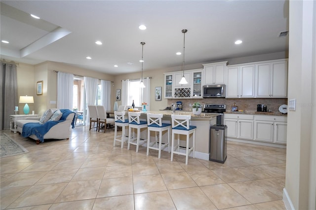 kitchen featuring a kitchen island with sink, white cabinetry, a kitchen breakfast bar, and appliances with stainless steel finishes