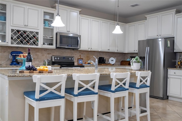 kitchen with white cabinets, appliances with stainless steel finishes, backsplash, and a kitchen breakfast bar