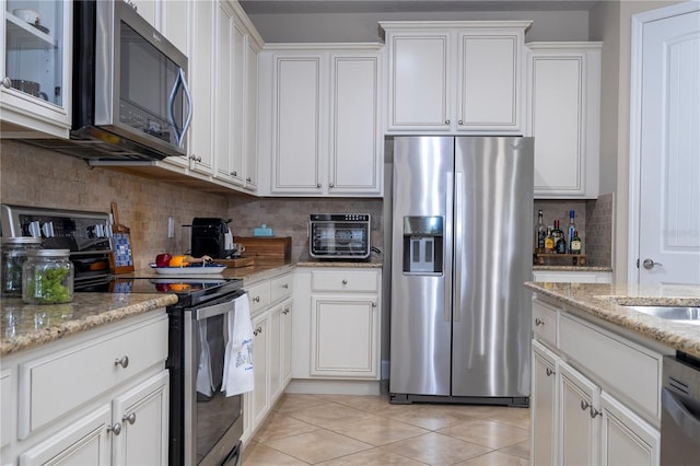 kitchen with white cabinetry, backsplash, light tile patterned flooring, and appliances with stainless steel finishes