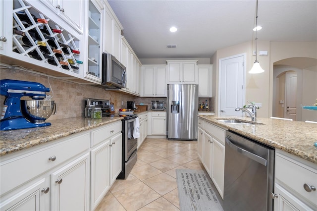 kitchen with pendant lighting, white cabinetry, sink, decorative backsplash, and stainless steel appliances