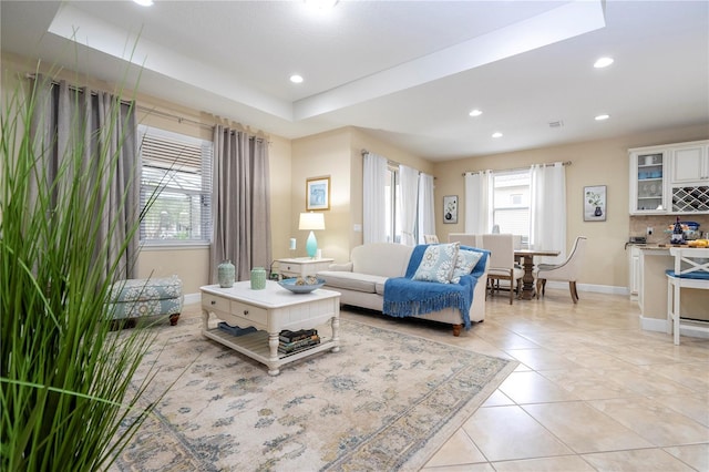 tiled living room featuring a raised ceiling