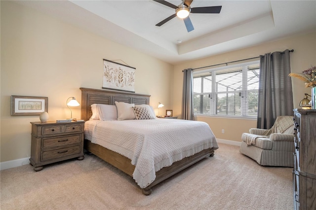 carpeted bedroom featuring ceiling fan and a tray ceiling