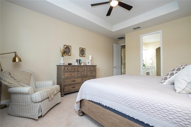 carpeted bedroom featuring connected bathroom, ceiling fan, and a tray ceiling