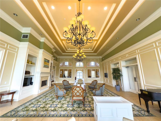 living room featuring built in shelves, a towering ceiling, a raised ceiling, and a notable chandelier