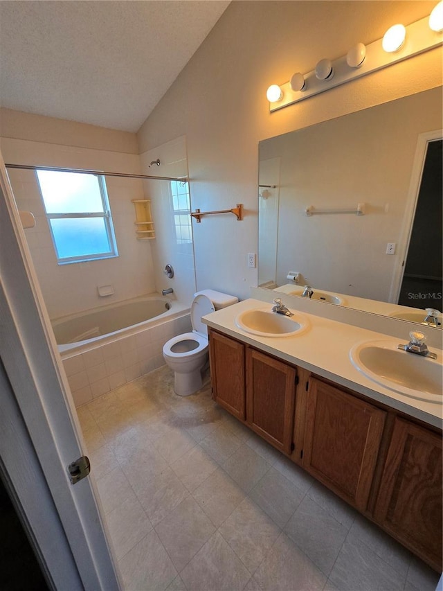 full bathroom with tiled shower / bath, lofted ceiling, vanity, toilet, and a textured ceiling