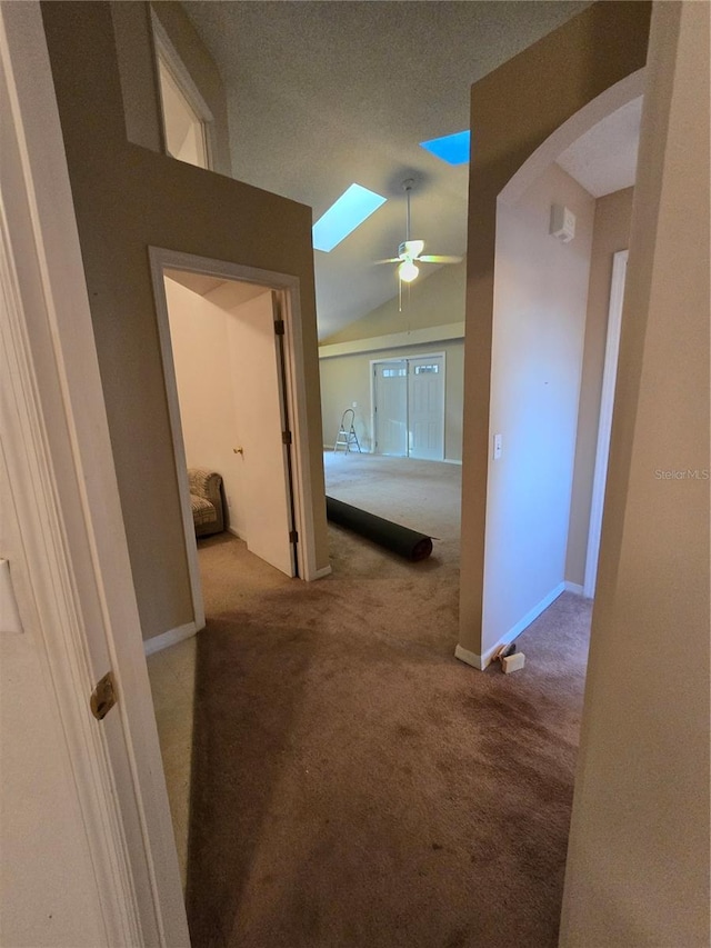 hall featuring lofted ceiling with skylight and light carpet