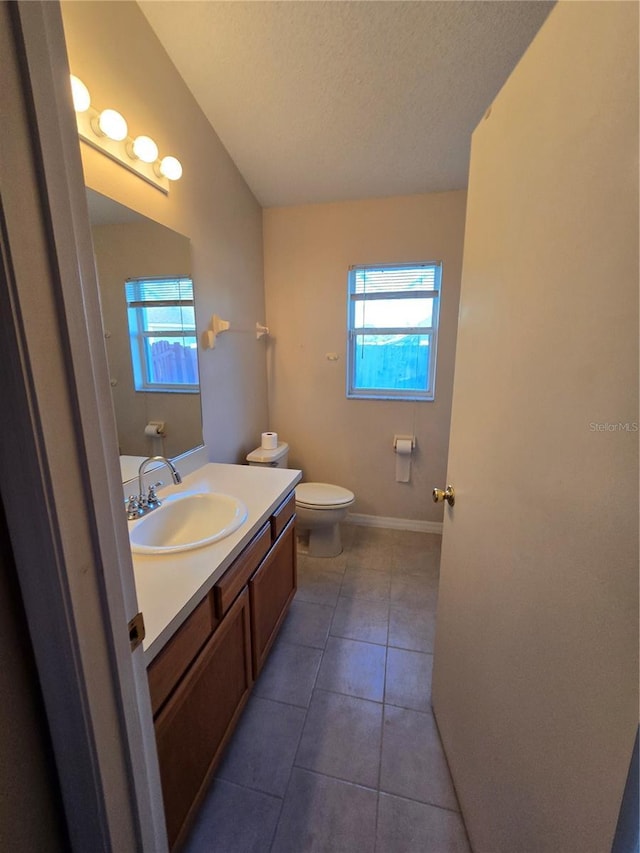 bathroom with tile patterned floors, toilet, vanity, and a wealth of natural light