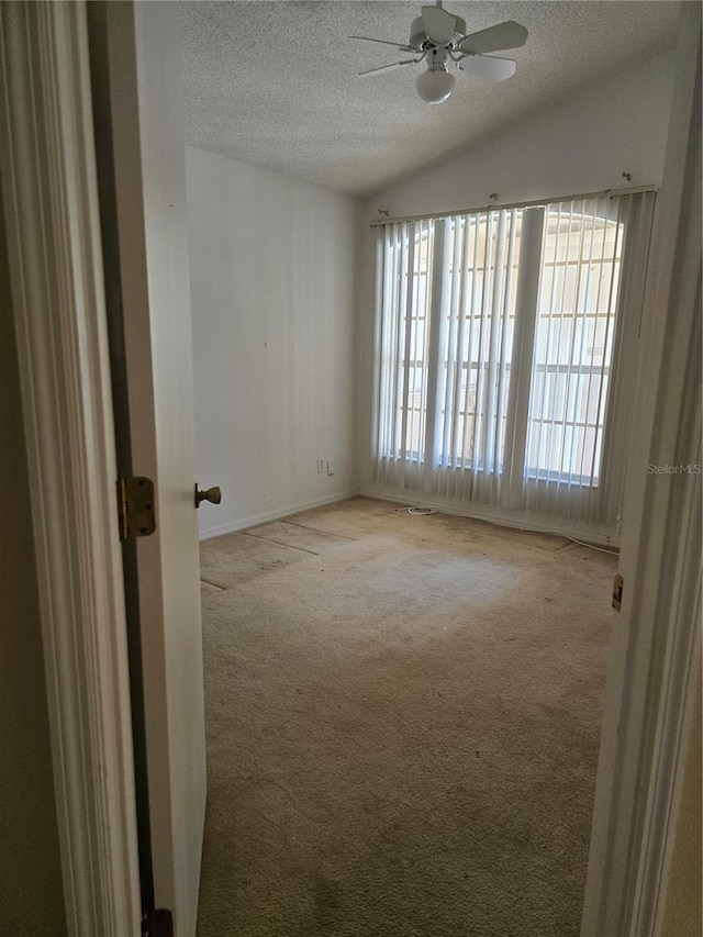 spare room featuring lofted ceiling, ceiling fan, light carpet, and a textured ceiling