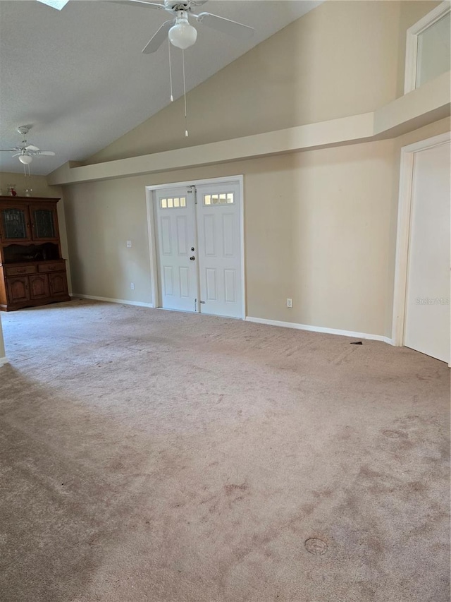 unfurnished living room with ceiling fan, carpet flooring, and high vaulted ceiling