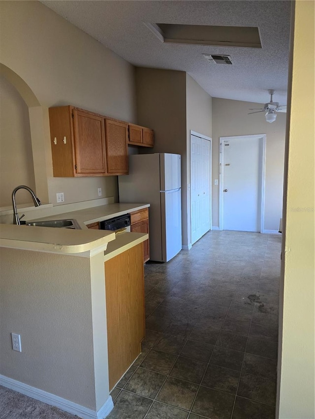 kitchen featuring lofted ceiling, sink, white fridge, kitchen peninsula, and a textured ceiling