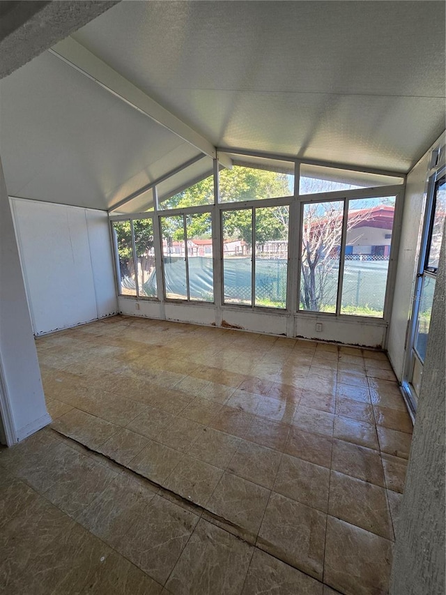 unfurnished sunroom with vaulted ceiling with beams