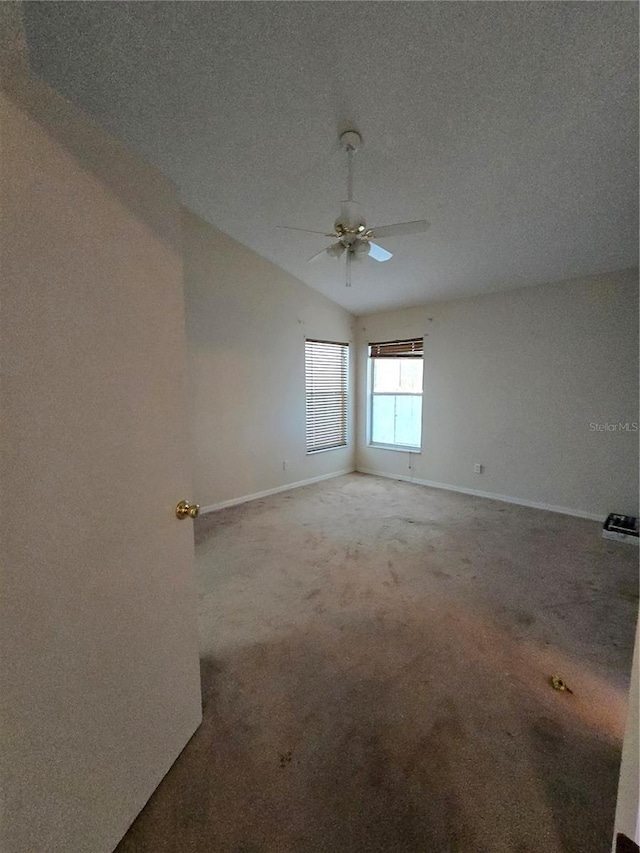 carpeted spare room featuring vaulted ceiling, a textured ceiling, and ceiling fan