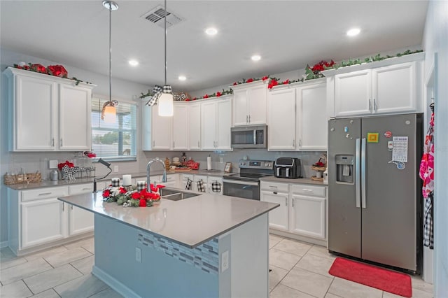 kitchen featuring decorative light fixtures, sink, white cabinets, a kitchen island with sink, and stainless steel appliances