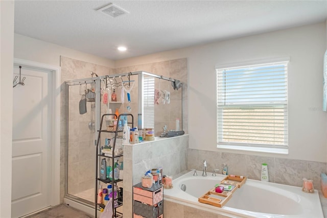 bathroom with independent shower and bath and a textured ceiling