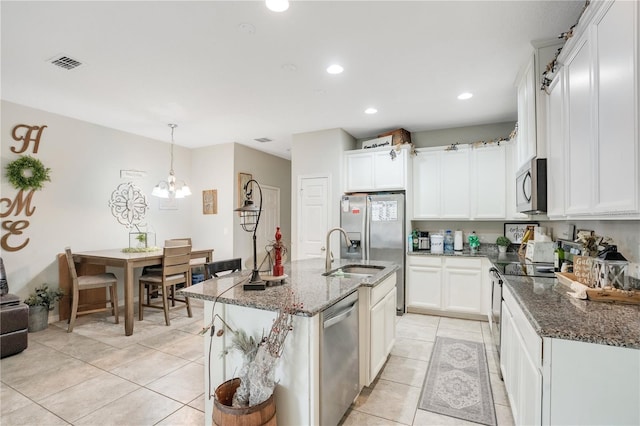 kitchen with sink, light tile patterned floors, appliances with stainless steel finishes, an island with sink, and white cabinets