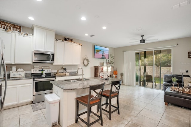 kitchen featuring sink, a breakfast bar area, stone counters, stainless steel appliances, and a center island with sink