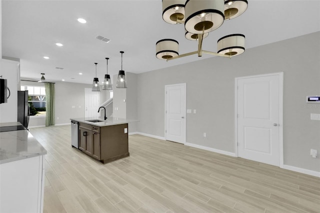 kitchen featuring sink, hanging light fixtures, light wood-type flooring, black refrigerator, and dishwasher