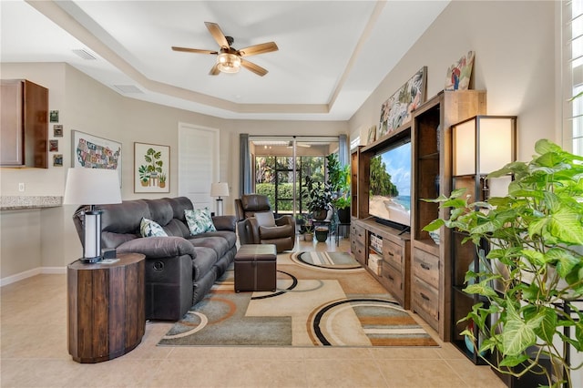 tiled living room with a raised ceiling and ceiling fan