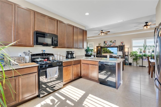 kitchen with light tile patterned floors, kitchen peninsula, ceiling fan, and black appliances