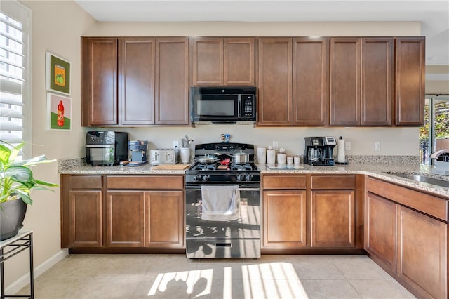 kitchen featuring sink, light tile patterned floors, and black appliances