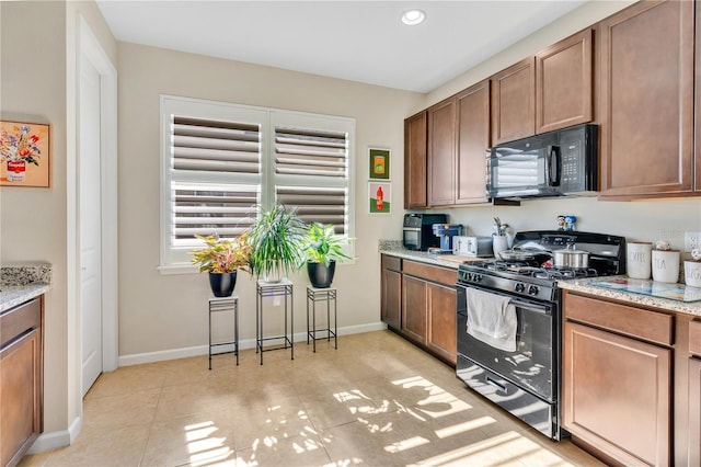 kitchen with gas range, light stone countertops, and light tile patterned flooring