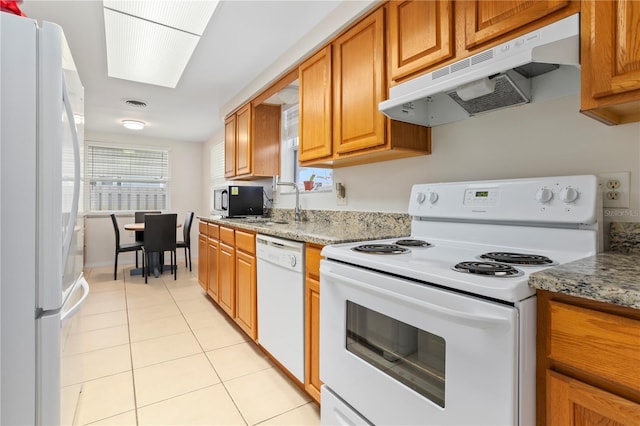 kitchen with light stone counters, white appliances, and light tile patterned floors