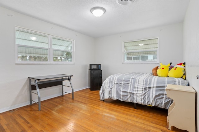 bedroom featuring hardwood / wood-style flooring and a textured ceiling