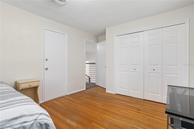 bedroom featuring hardwood / wood-style floors, a textured ceiling, and a closet