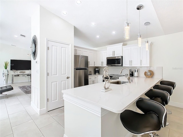 kitchen featuring sink, vaulted ceiling, kitchen peninsula, pendant lighting, and stainless steel appliances