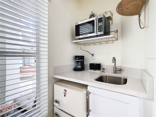 kitchen with sink, fridge, and white cabinets