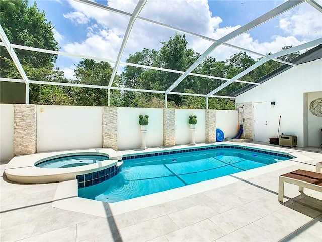 view of pool with a patio, glass enclosure, and an in ground hot tub