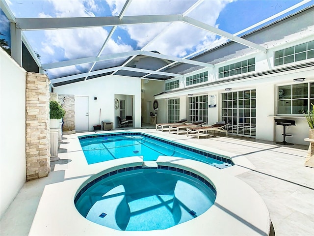 view of pool with a patio area, an in ground hot tub, and glass enclosure