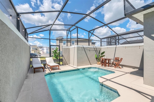 view of pool with glass enclosure and a patio area