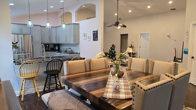 dining room featuring sink, dark wood-type flooring, high vaulted ceiling, and ceiling fan